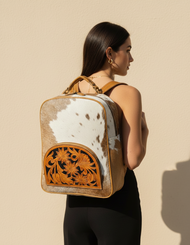 Tan and white hair-on leather backpack with tooled sunflower front pocket, tan leather trim and antique brass hardware