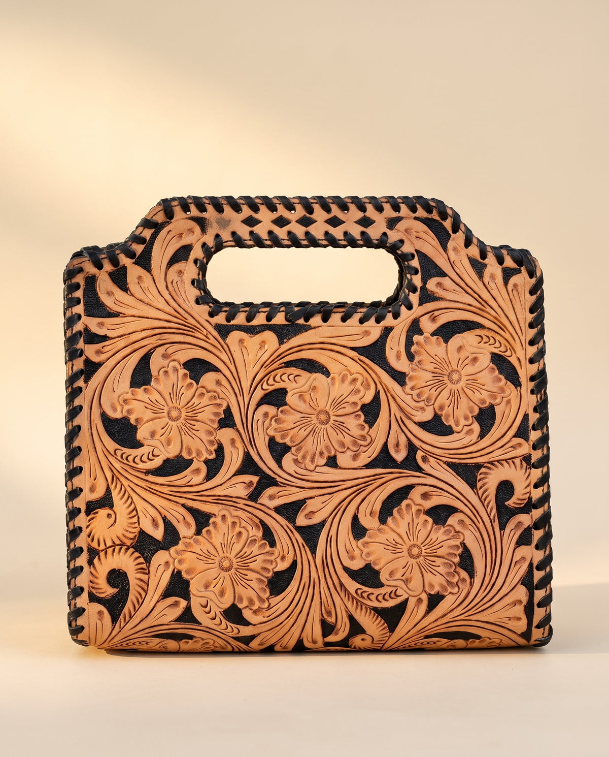 Black hand-tooled leather bag with cut-out handle, front view, by Ya Qalbi
