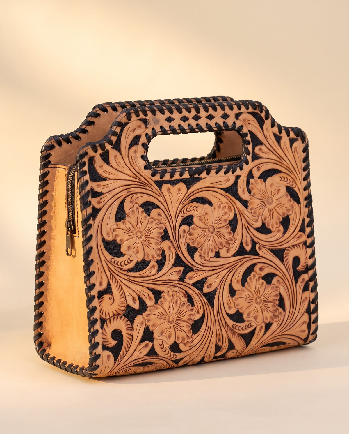 Black hand-tooled leather bag with cut-out handle, angled view, by Ya Qalbi