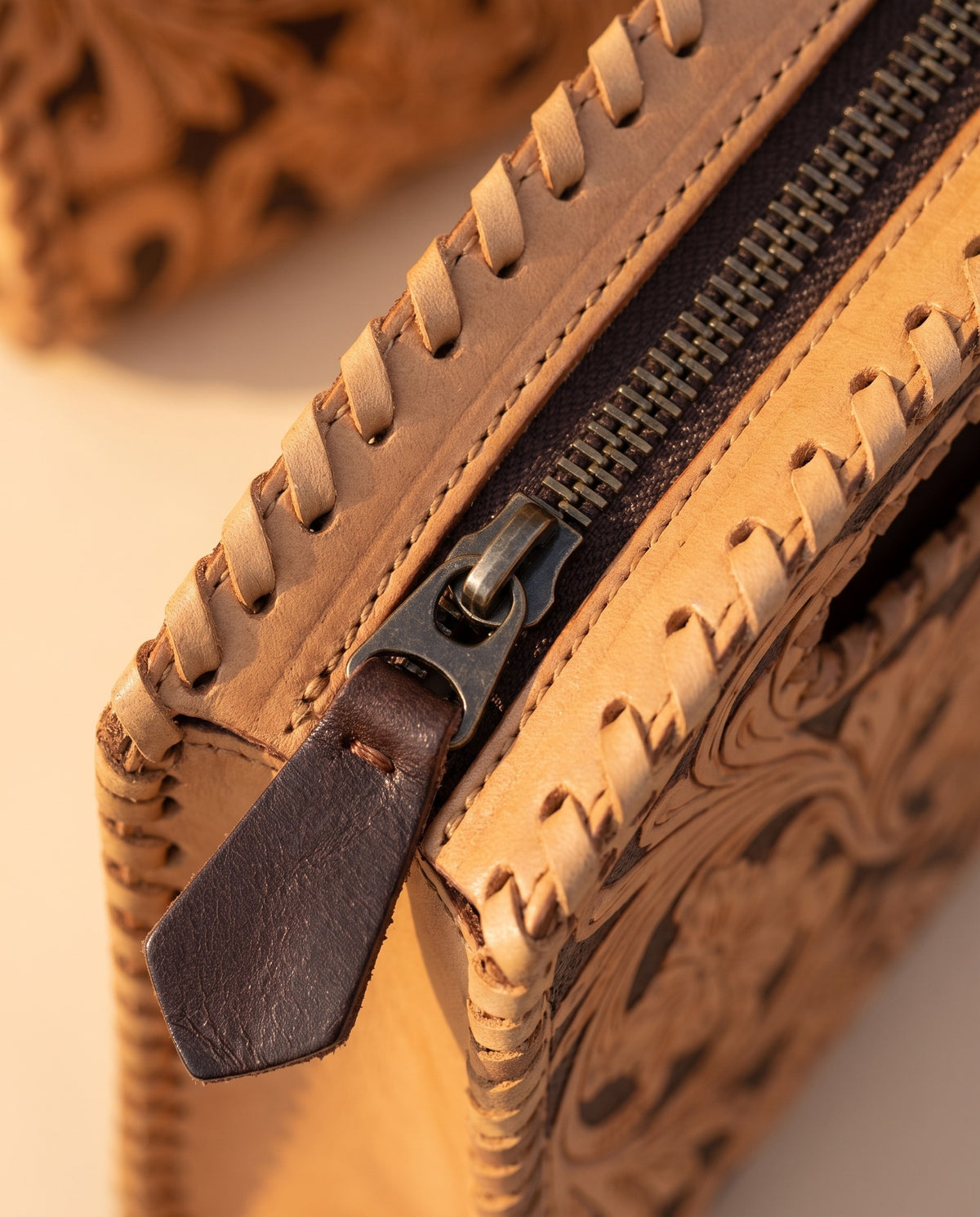 Brown hand-tooled leather bag with cut-out handle, detail close-up, by Ya Qalbi
