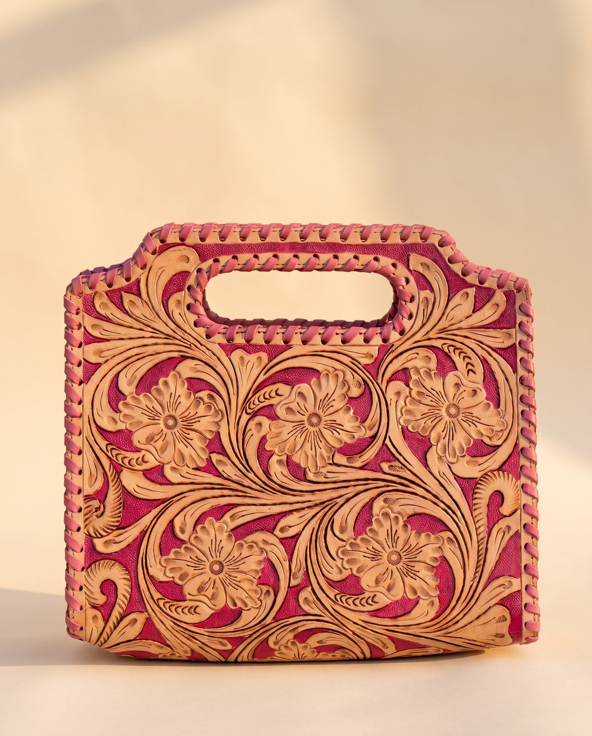 Pink hand-tooled leather bag with cut-out handle, front view, by Ya Qalbi