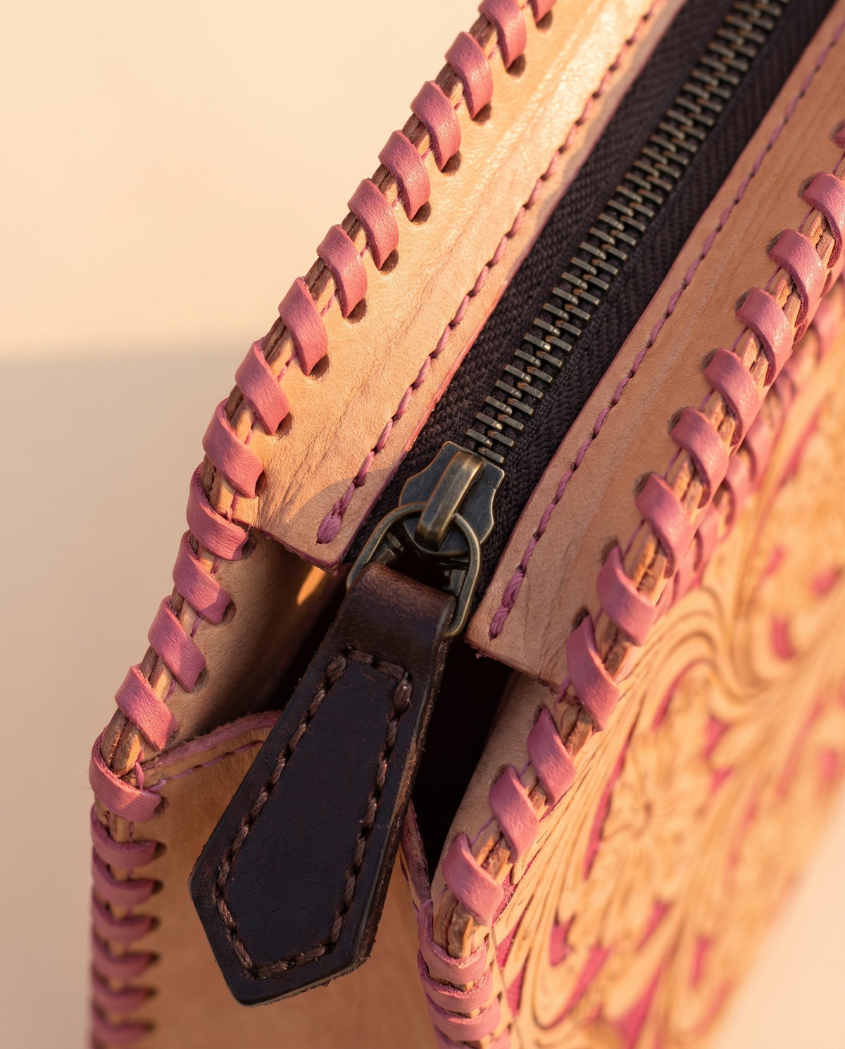 Pink hand-tooled leather bag with cut-out handle, detail close-up, by Ya Qalbi