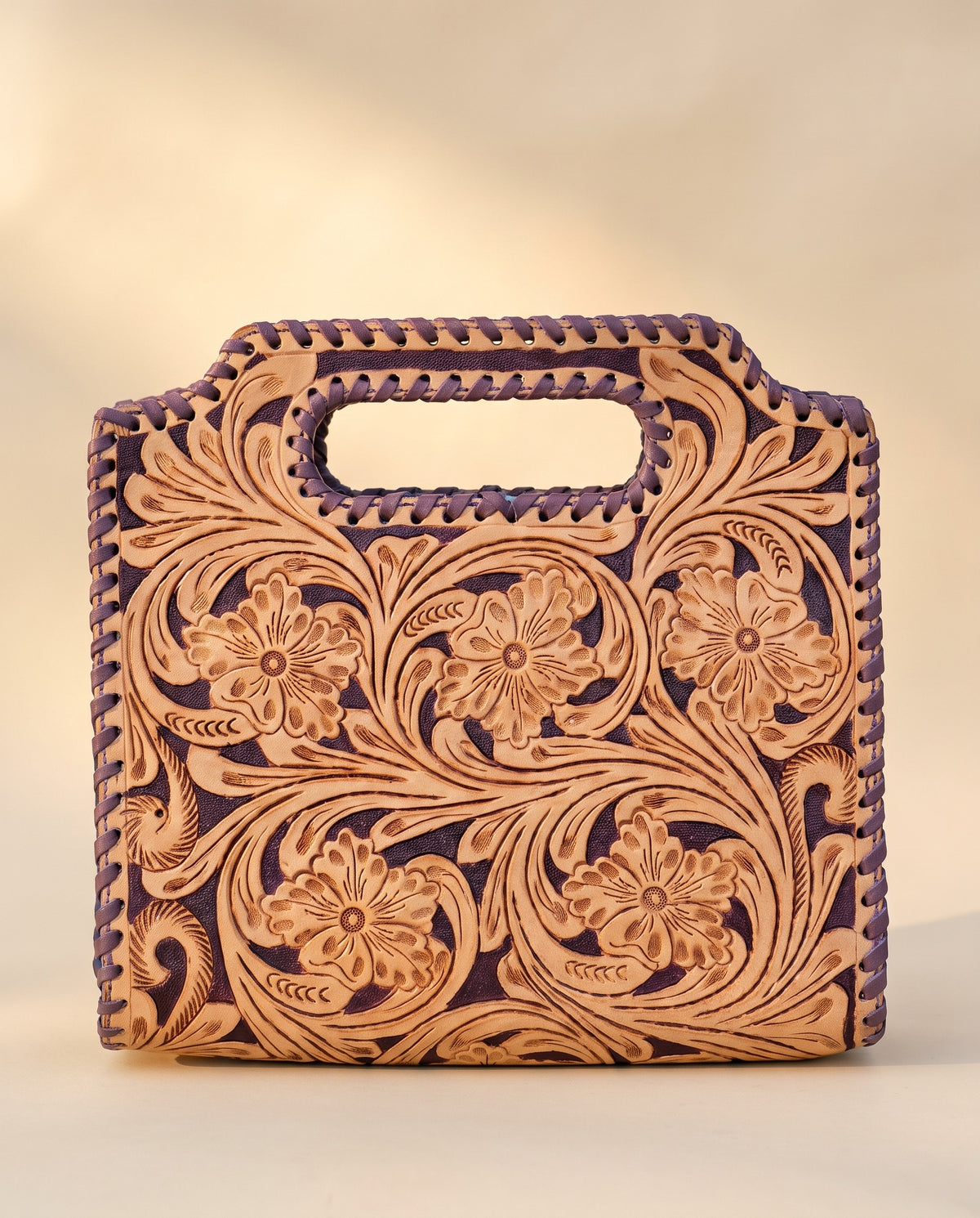Purple hand-tooled leather bag with cut-out handle, front view, by Ya Qalbi