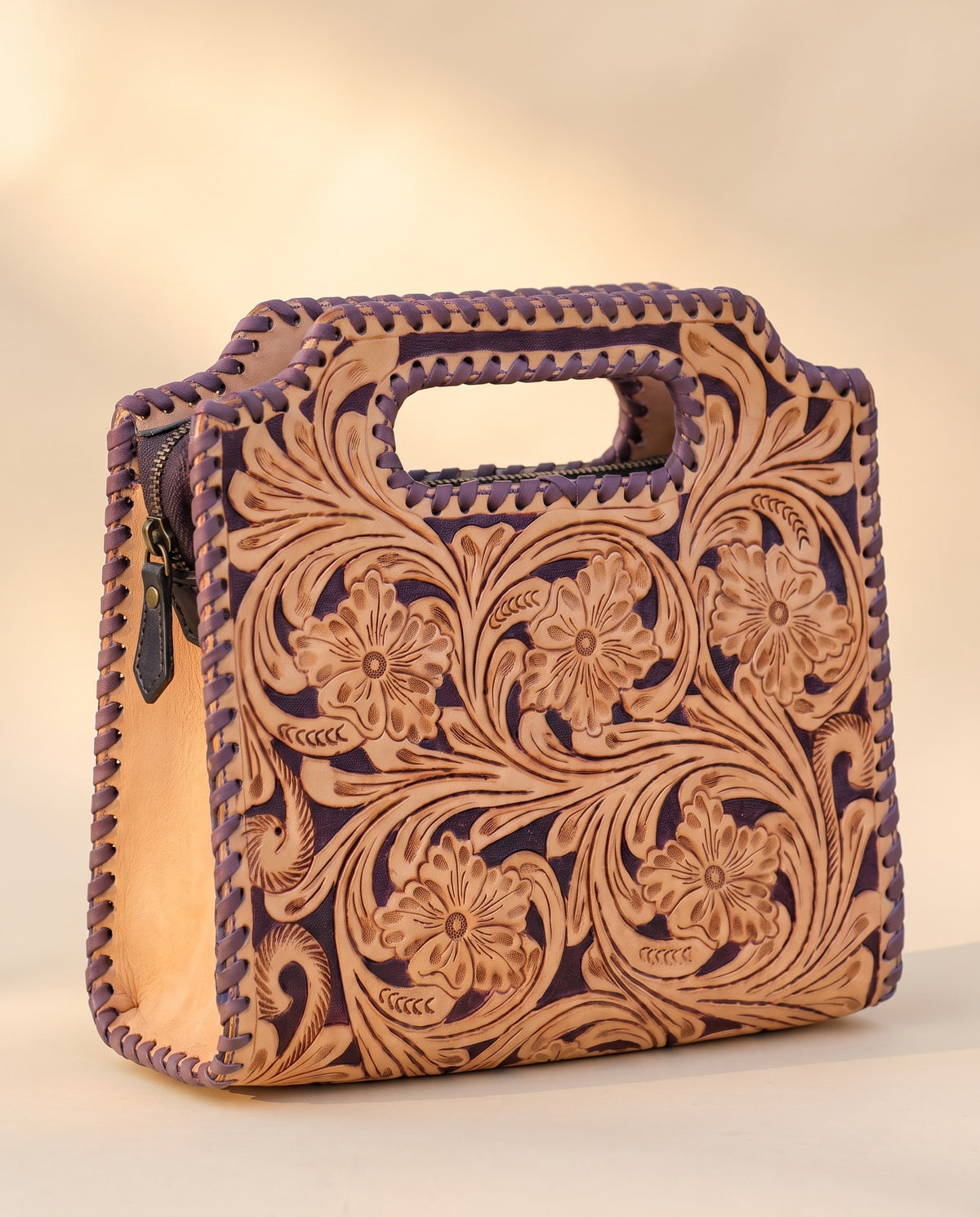 Purple hand-tooled leather bag with cut-out handle, angled view, by Ya Qalbi