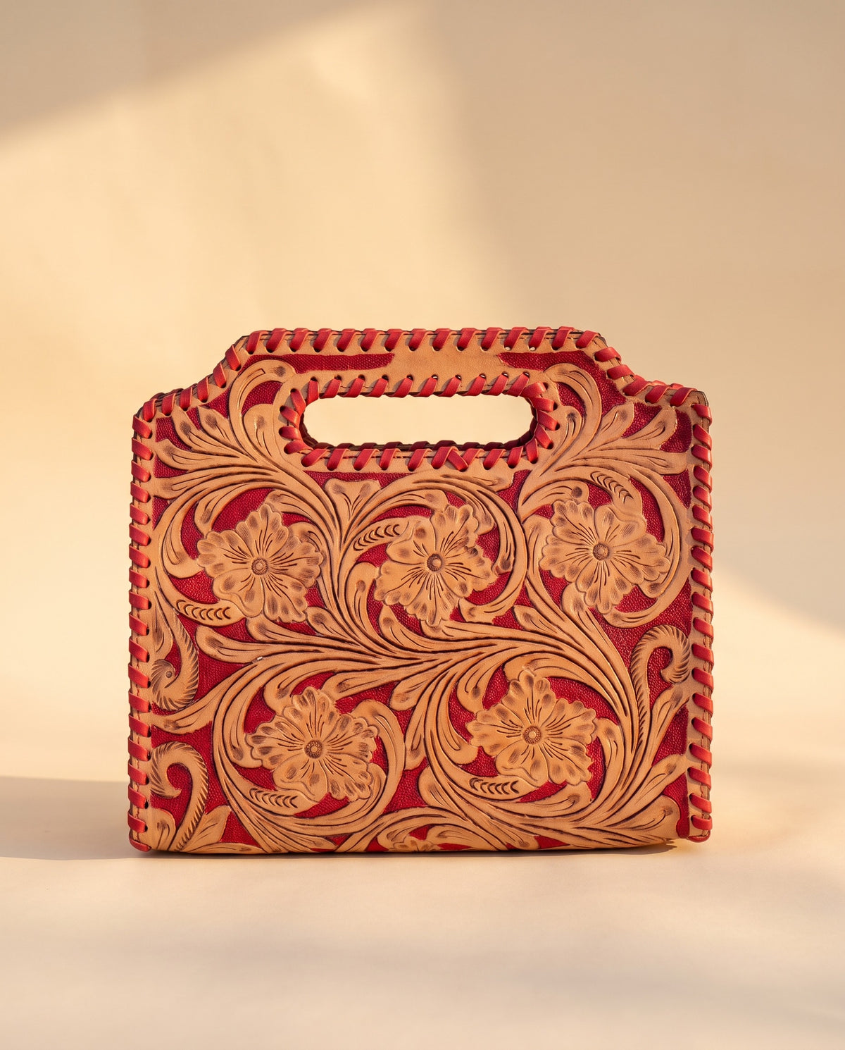 Red hand-tooled leather bag with cut-out handle, front view, by Ya Qalbi