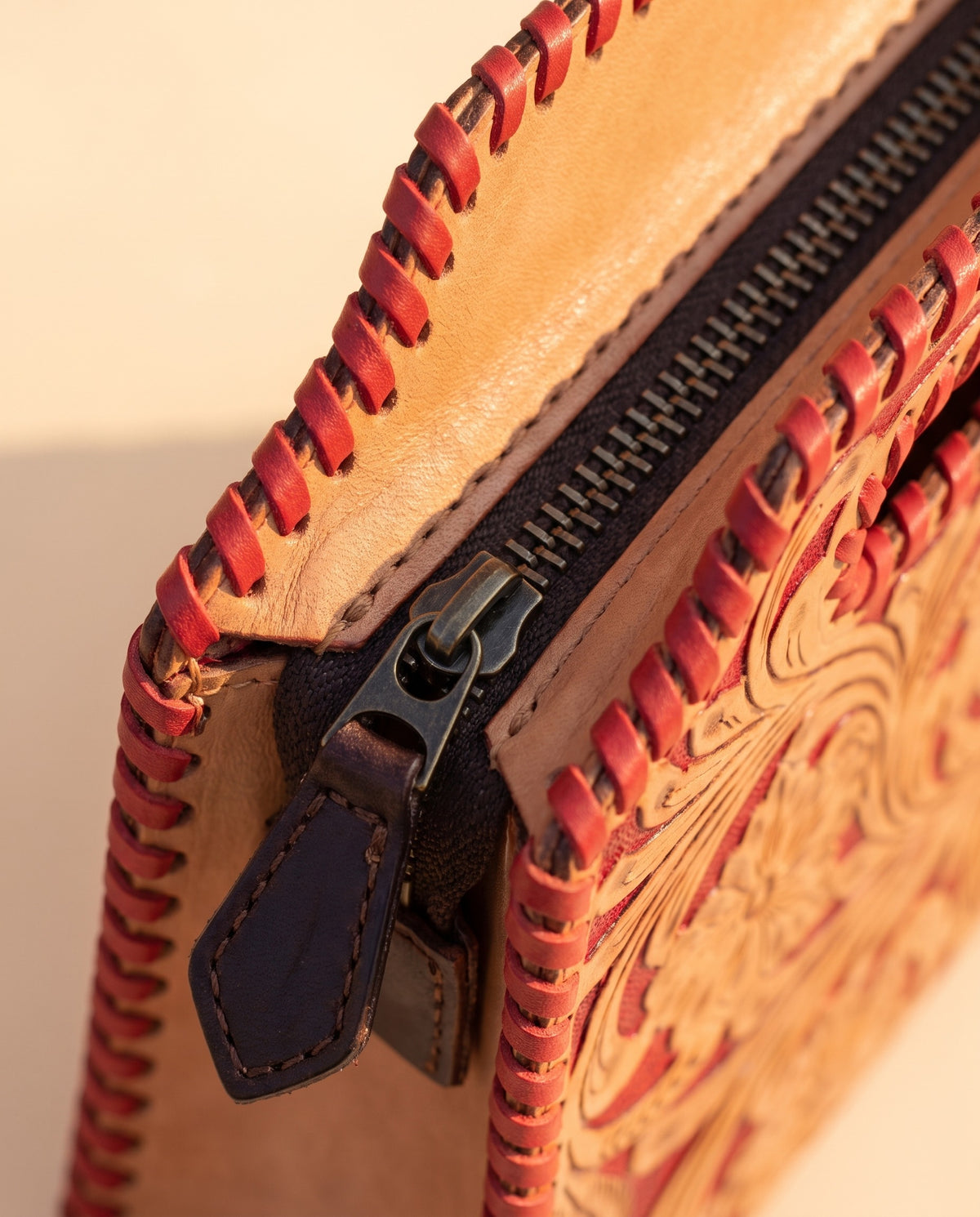 Red hand-tooled leather bag with cut-out handle, detail close-up, by Ya Qalbi