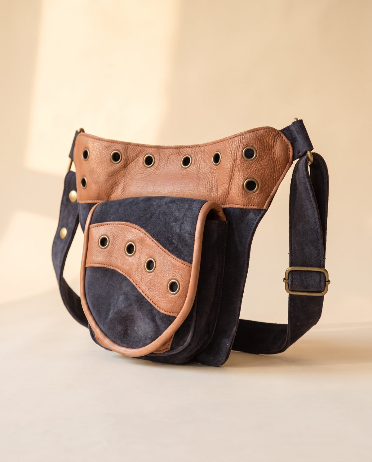 Navy and tan eyelet suede hip bag, angled view, by Ya Qalbi