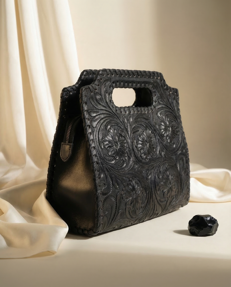 Full-grain black leather top-handle clutch tote with artisan tooling by Ya Qalbi