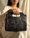 Black artisan leather clutch tote with floral hand-tooling by Ya Qalbi