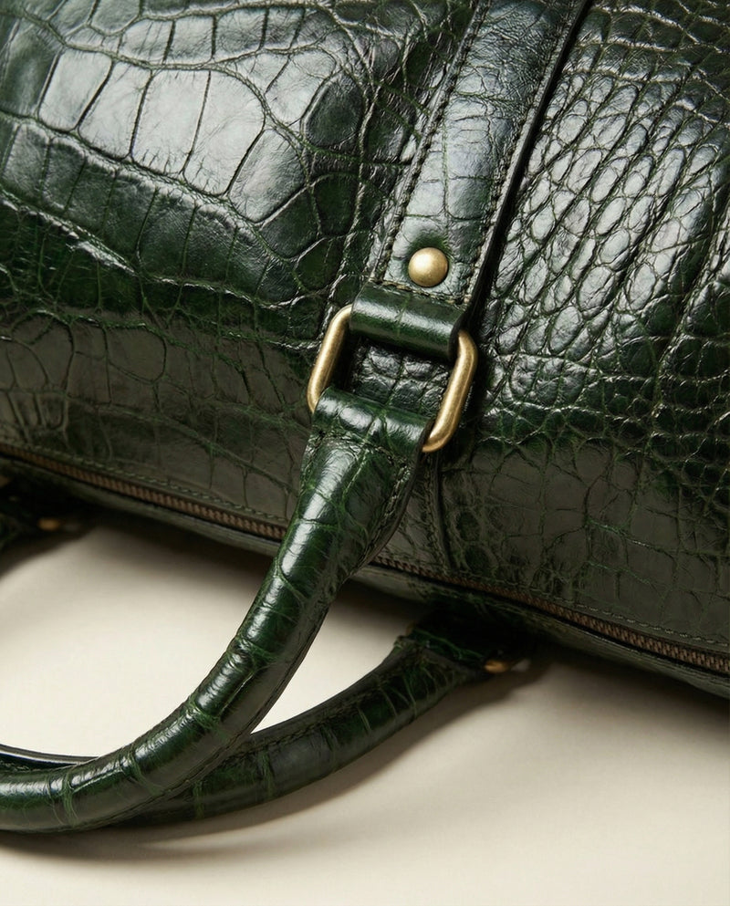 Green croc-textured leather travel bag with brass studs by Ya Qalbi