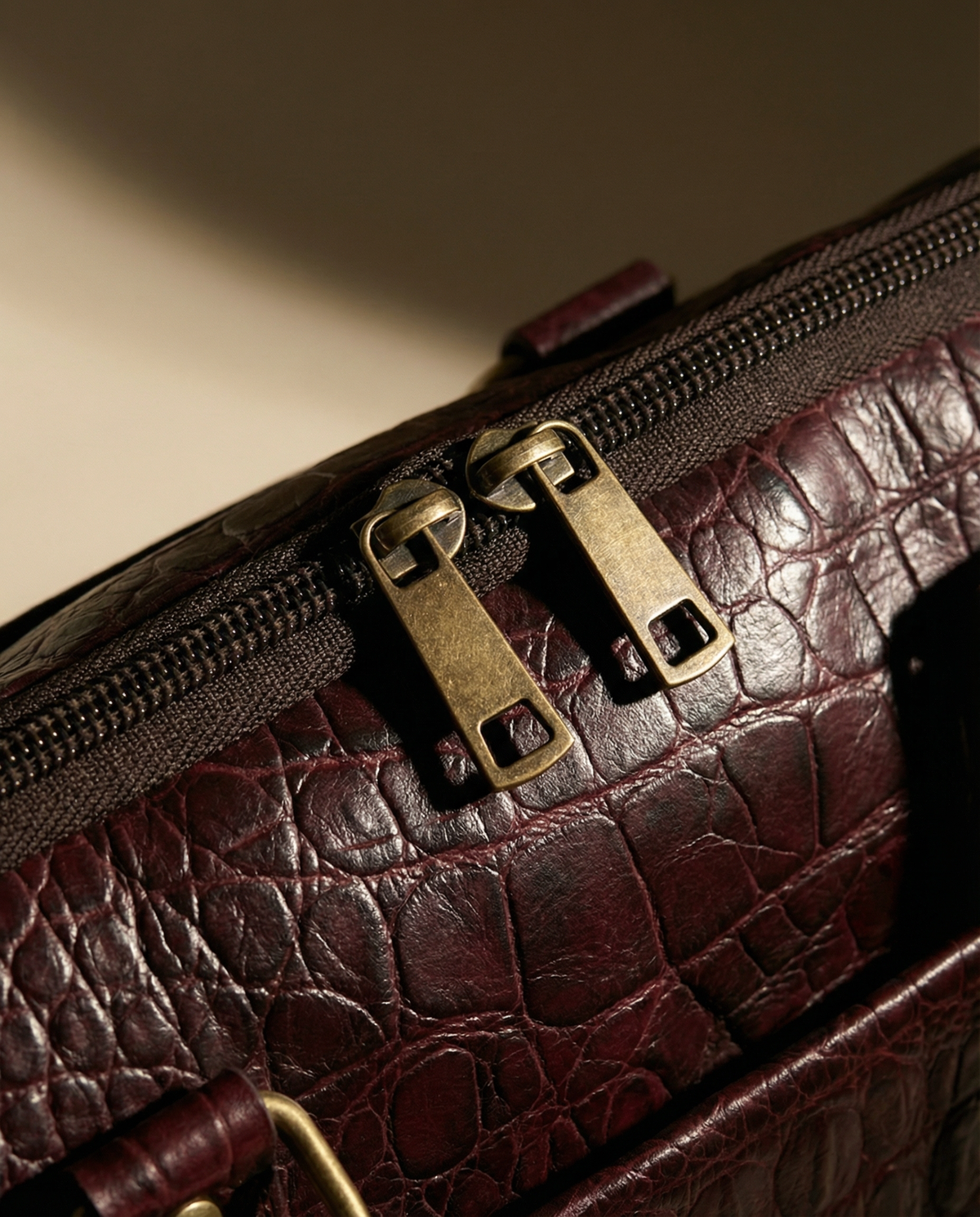 Close-up of double zip pulls on oxblood croc leather