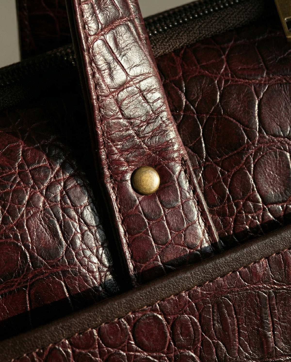 Close-up of riveted handle on oxblood croc leather