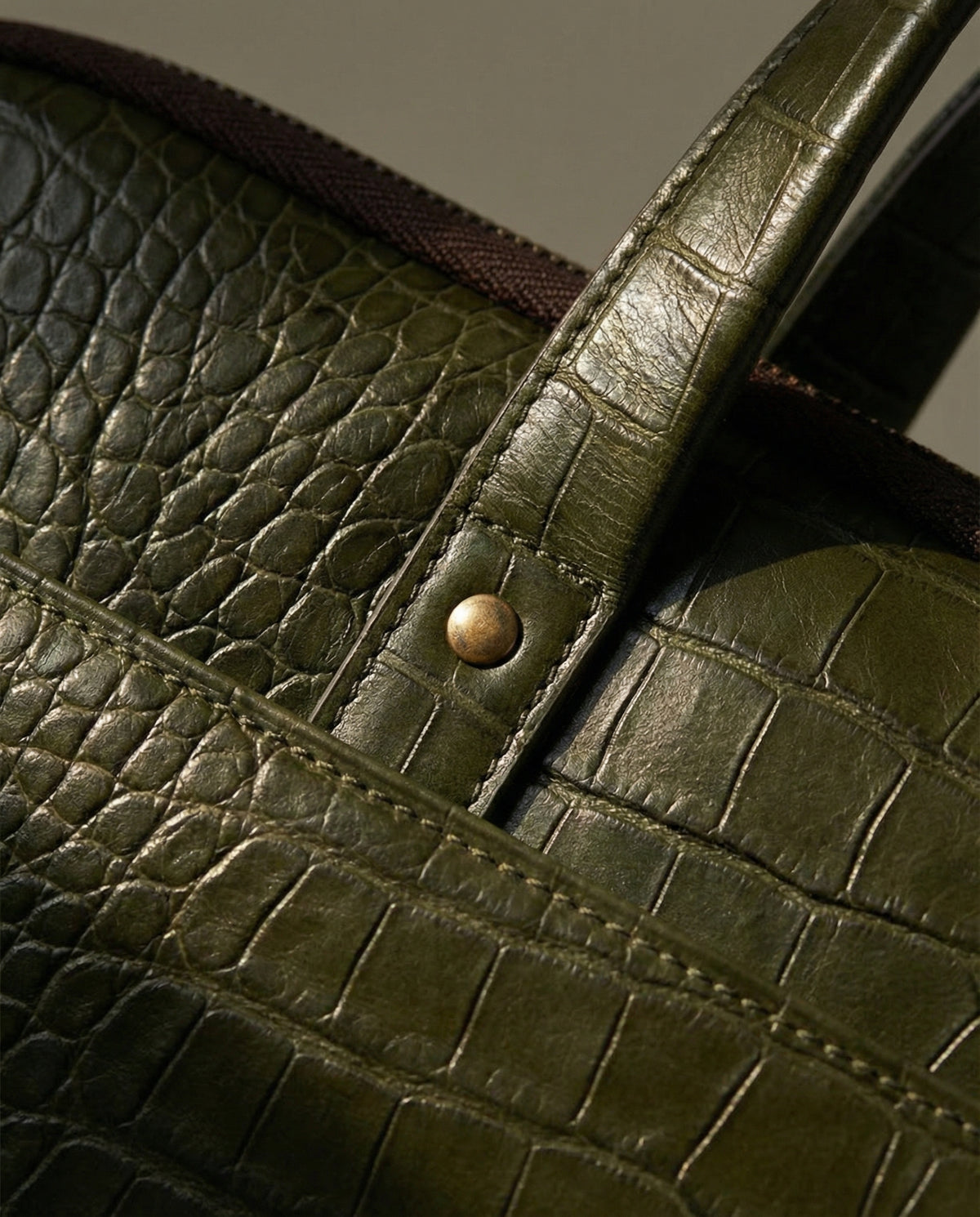 Close-up of rolled handle on olive green croc leather