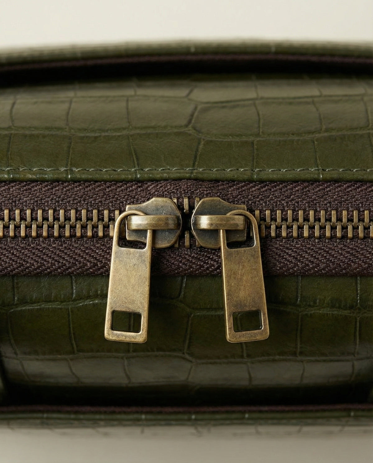 Close-up of double zip pulls on olive green croc leather