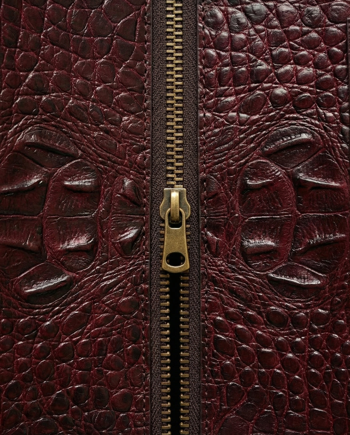 Close-up of zip on wine croc-embossed leather