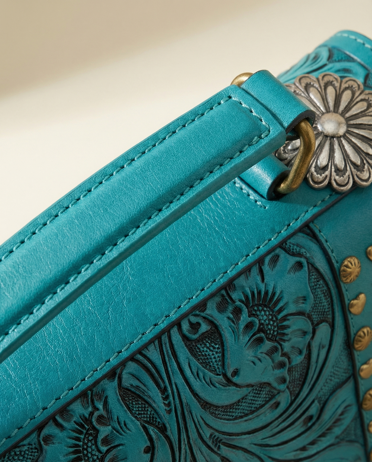 Close-up of top handle and silver concho on turquoise tooled satchel by Ya Qalbi