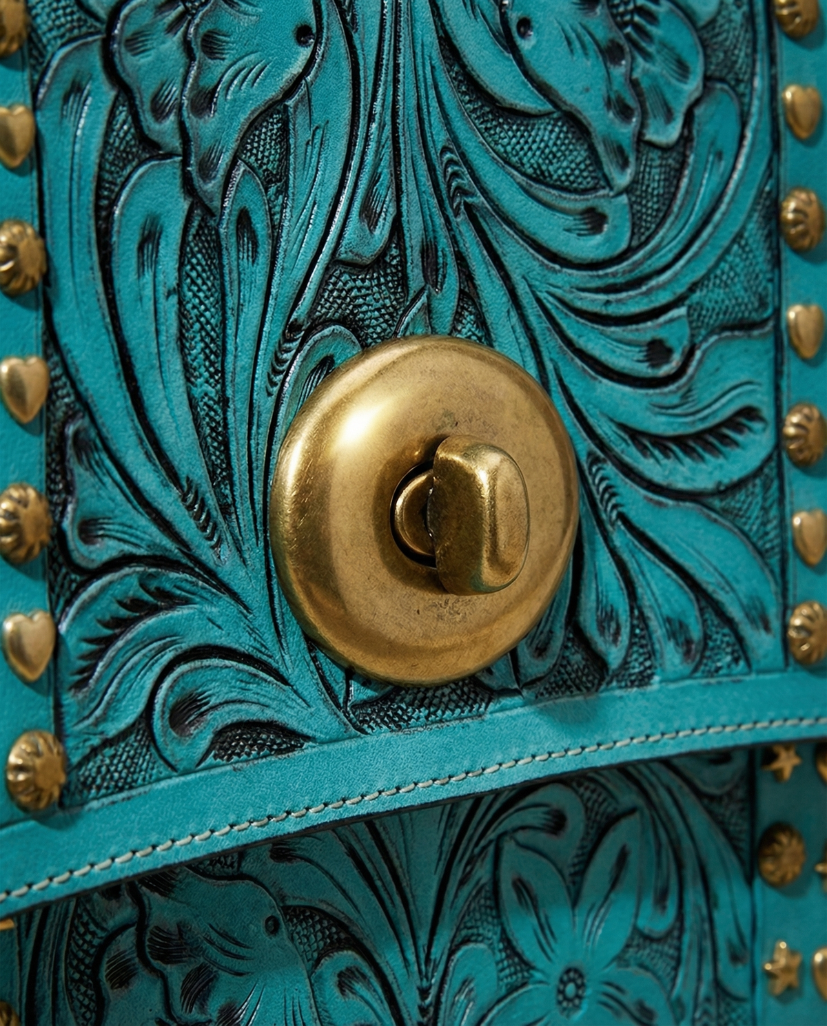 Close-up of floral carving and brass turn-lock on turquoise satchel by Ya Qalbi