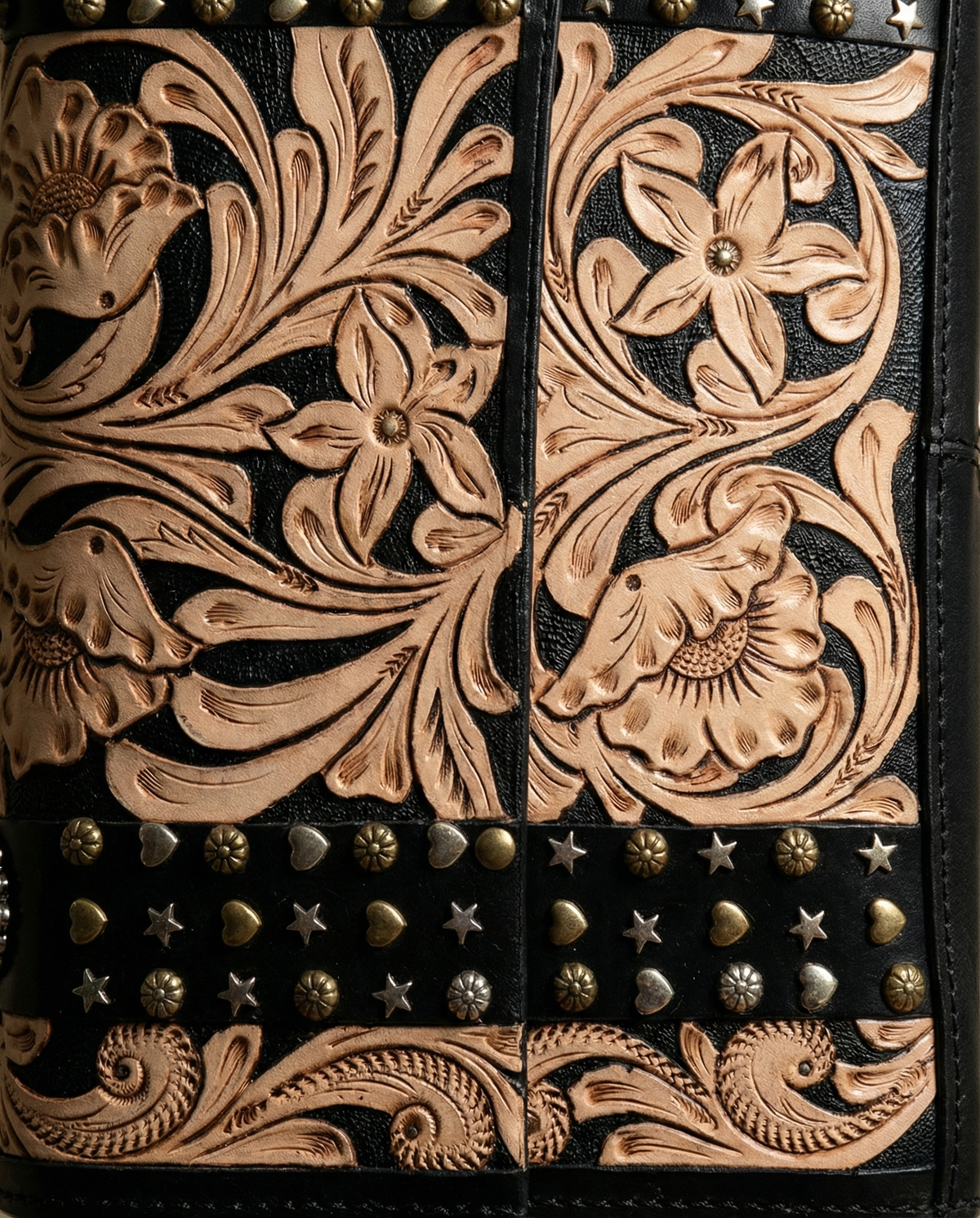 Close-up of contrast floral carving and brass studs on black leather by Ya Qalbi