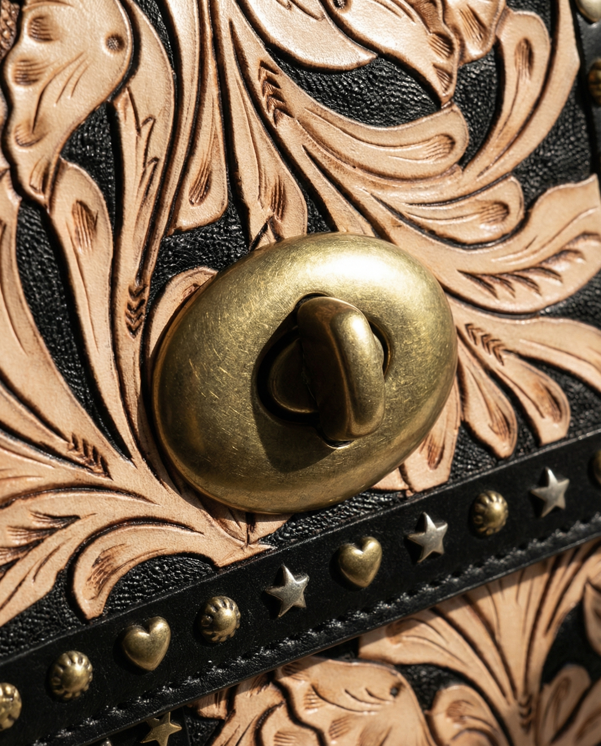 Close-up of brass turn-lock on midnight black tooled satchel by Ya Qalbi