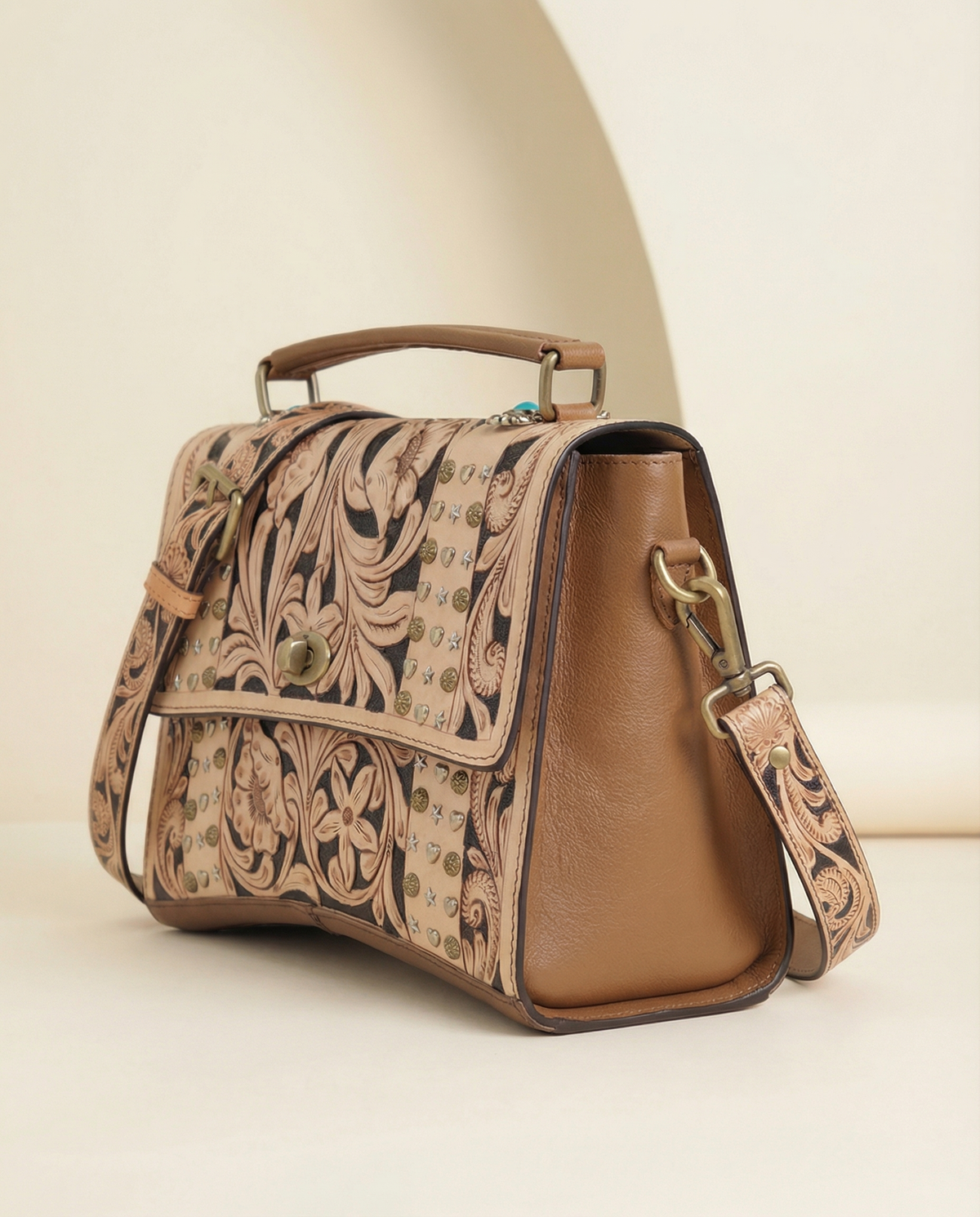 Tan tooled leather crossbody satchel with brass studs, angled view, by Ya Qalbi