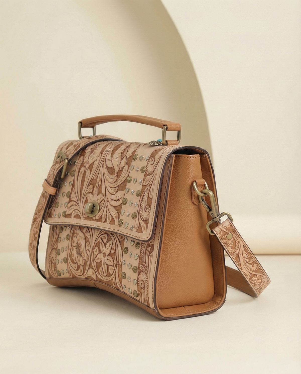 Side angle of tan tooled leather satchel with top handle by Ya Qalbi