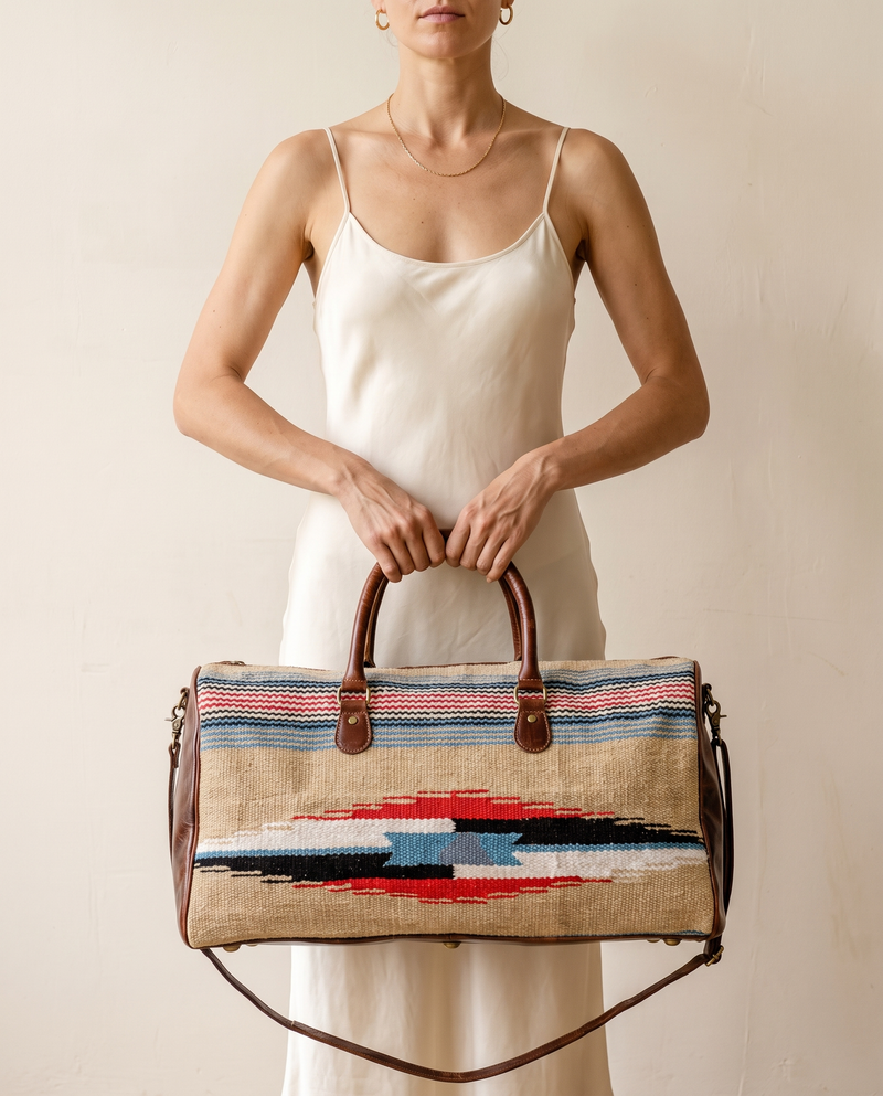 Woman holding sand kilim duffle bag with dark brown leather trim