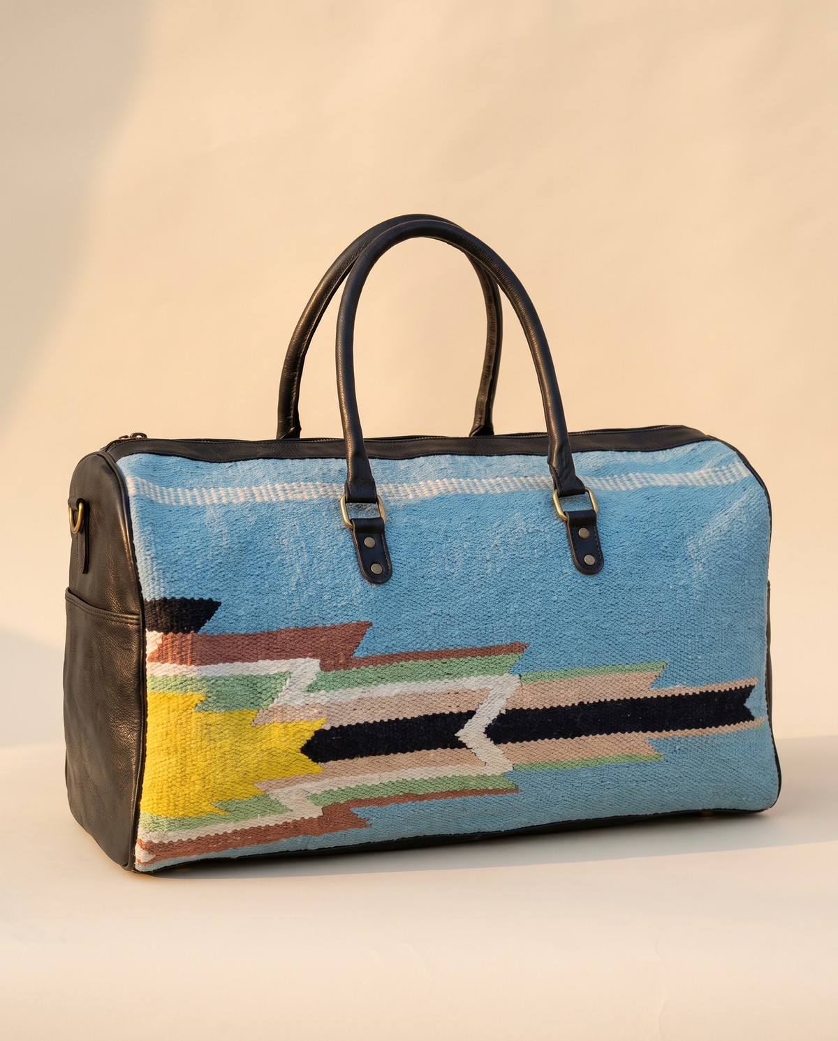 Sky blue kilim duffle bag with black leather ends and yellow, green and navy motif
