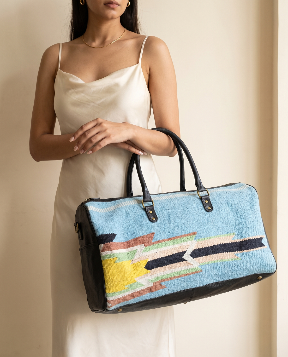 Woman holding sky blue kilim and black leather duffle bag
