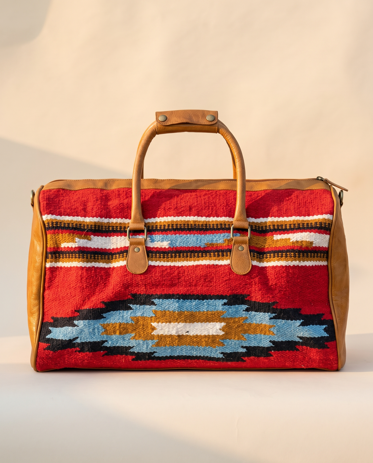 Red kilim duffle bag with blue and mustard diamond and tan leather, front view