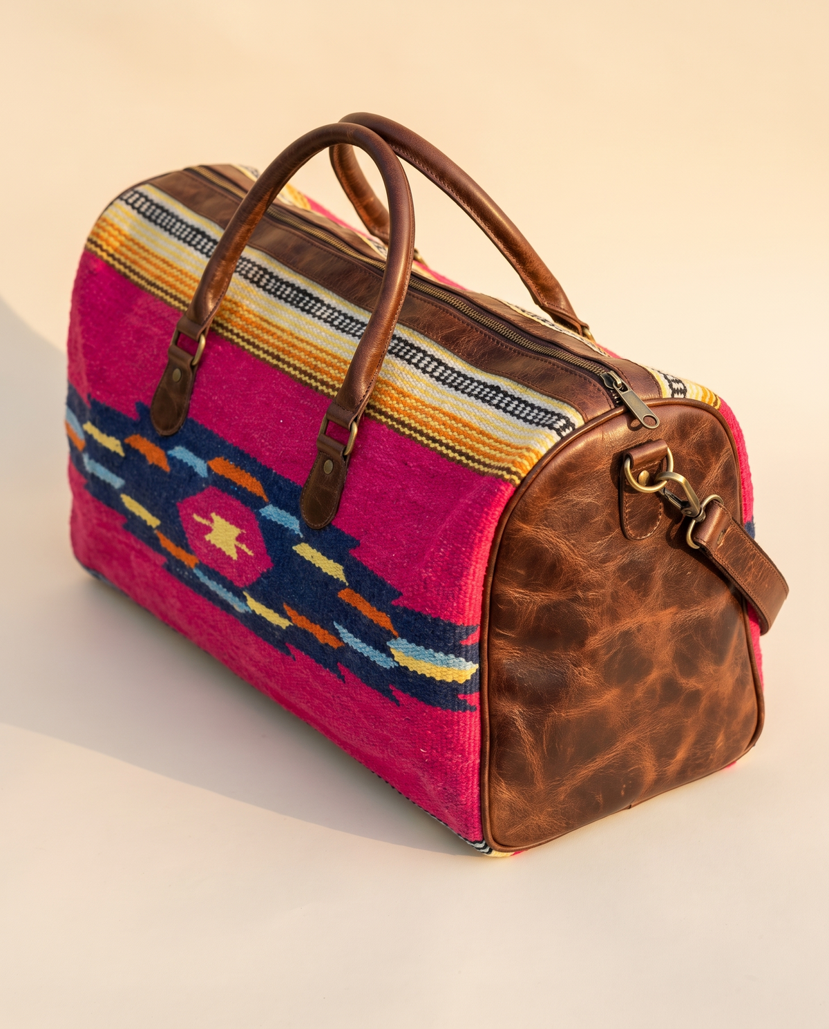 Fuchsia kilim weekender with distressed brown leather end panel, angled view