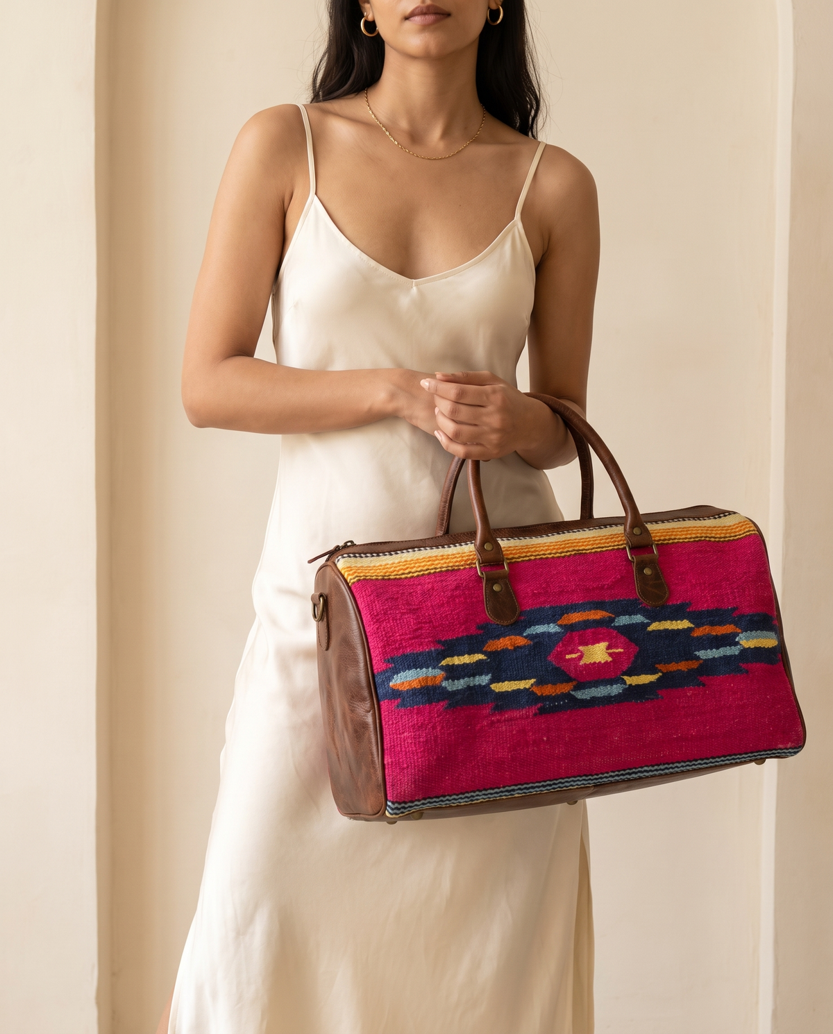 Woman holding fuchsia kilim duffle bag with dark brown leather trim