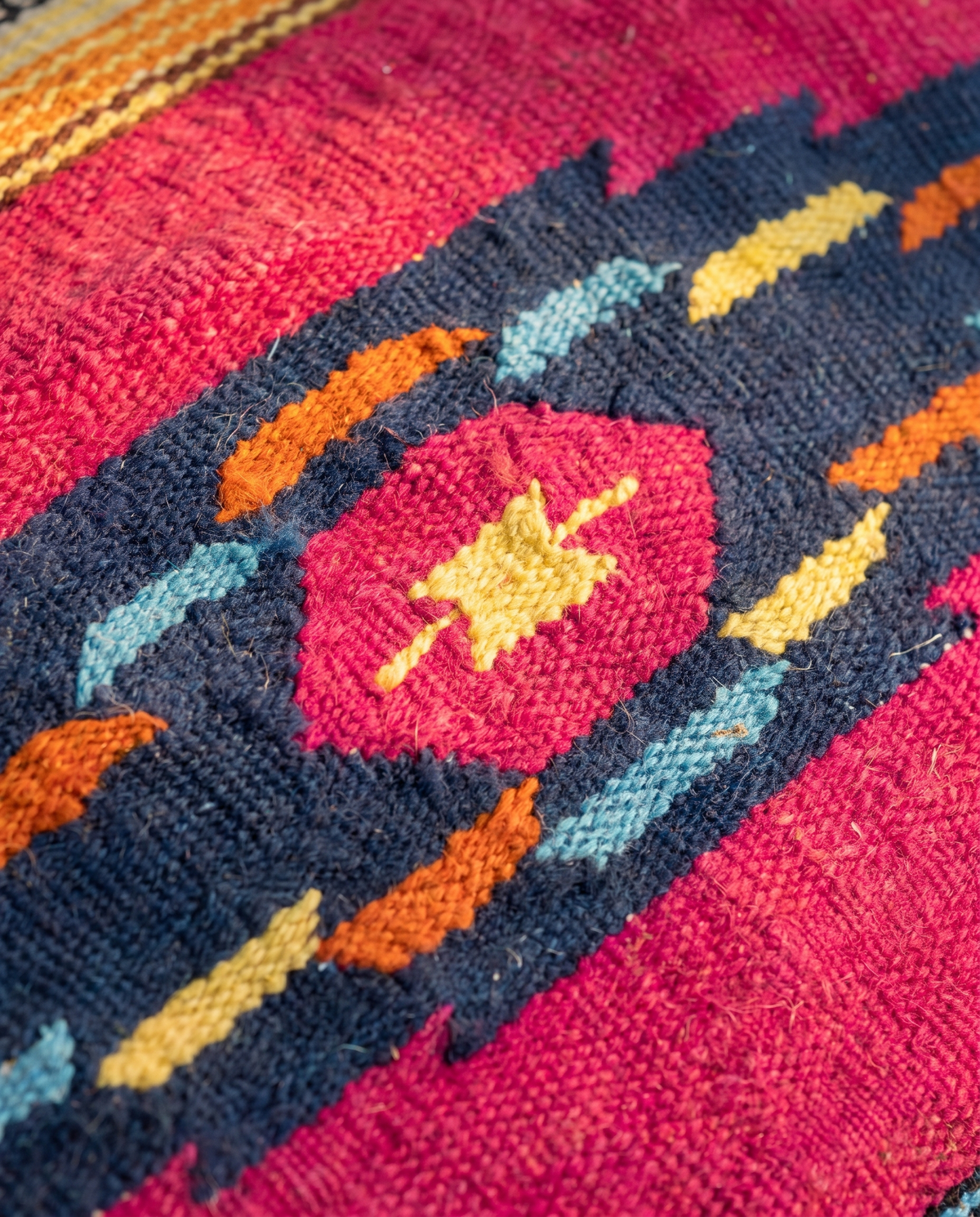 Detail of navy band with pink hexagon and orange, yellow and blue flecks on fuchsia kilim