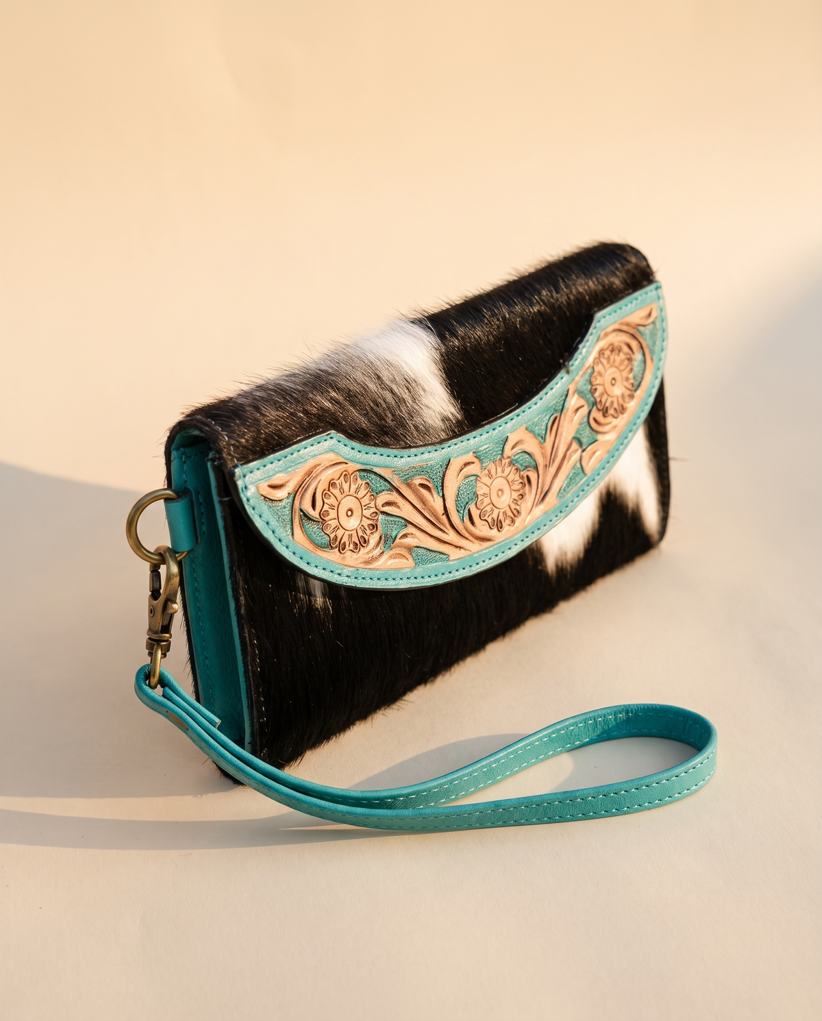 Turquoise cowhide wallet with curved hand-tooled flap, angled view, by Ya Qalbi