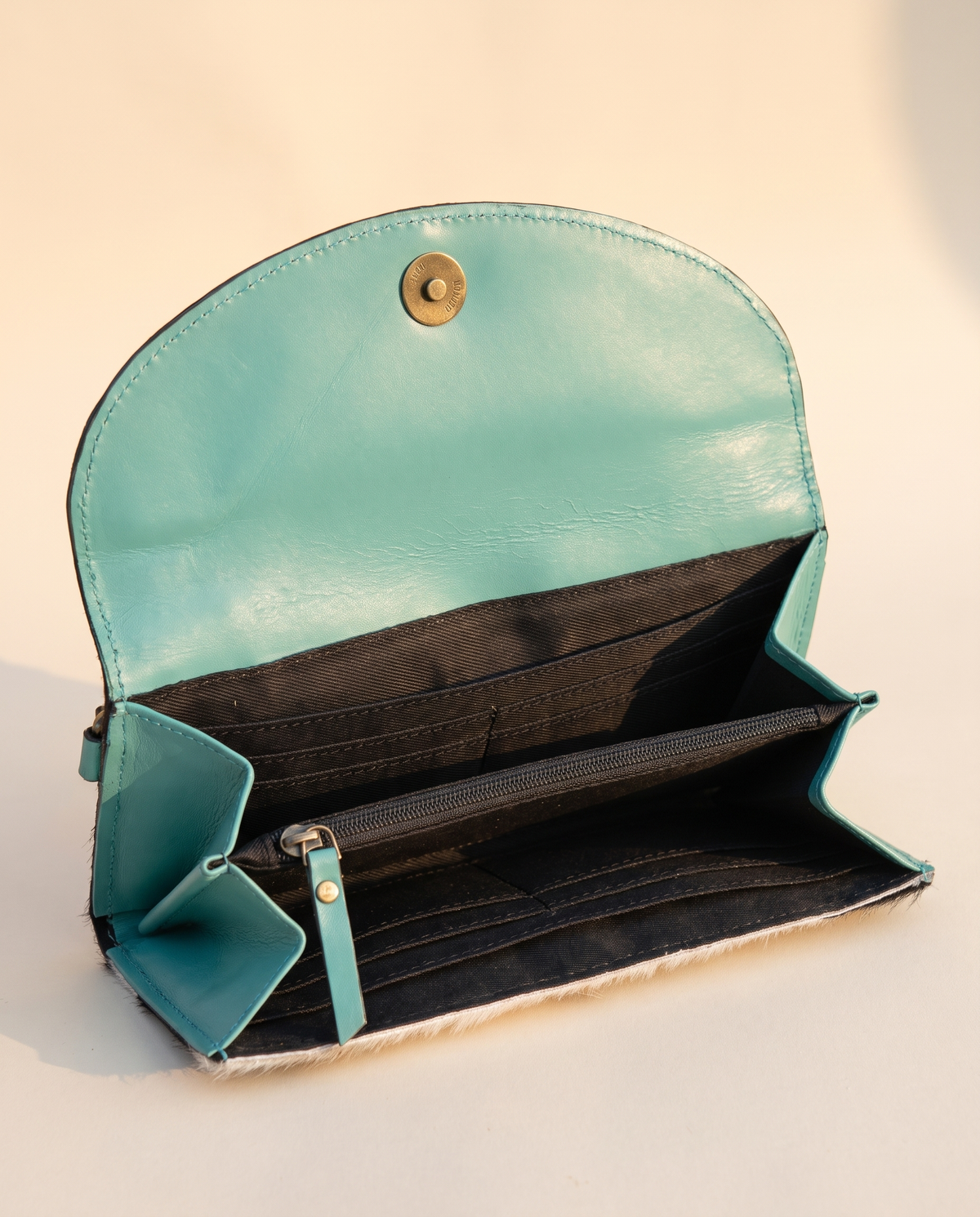 Turquoise cowhide wallet with curved hand-tooled flap, open interior view, by Ya Qalbi