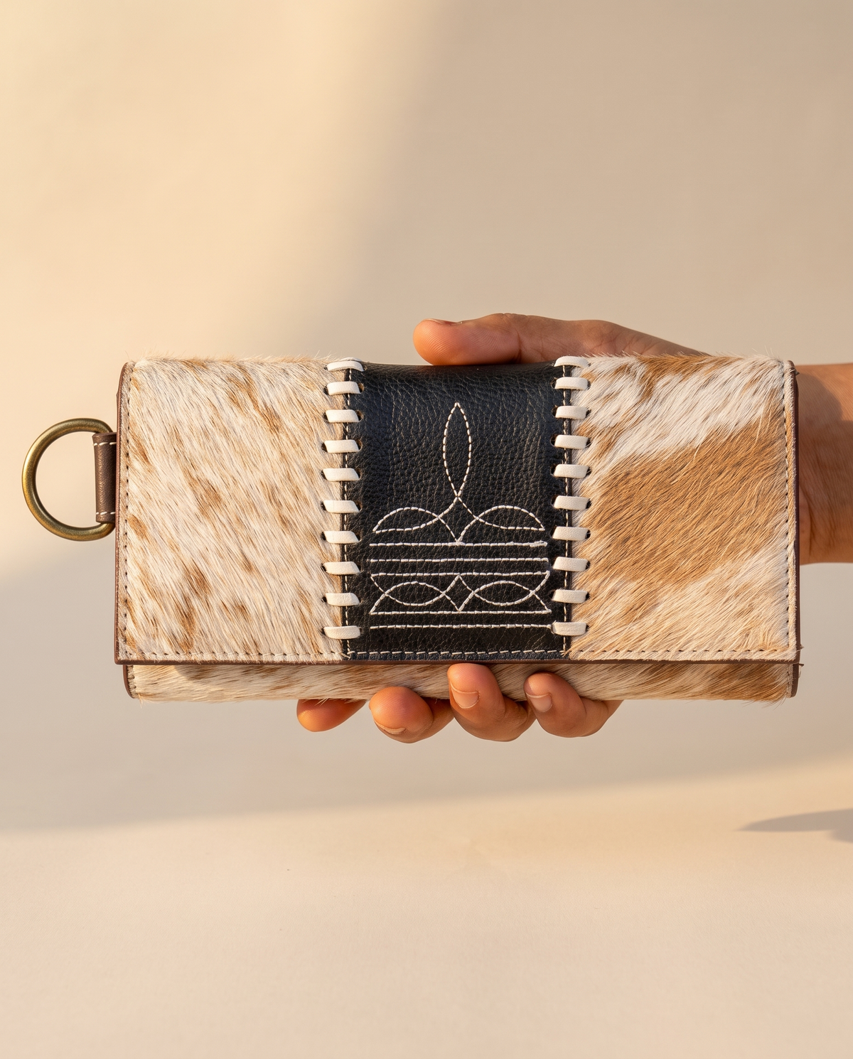 Tan and Black cowhide wallet with bootstitch leather panel, held in hand, by Ya Qalbi