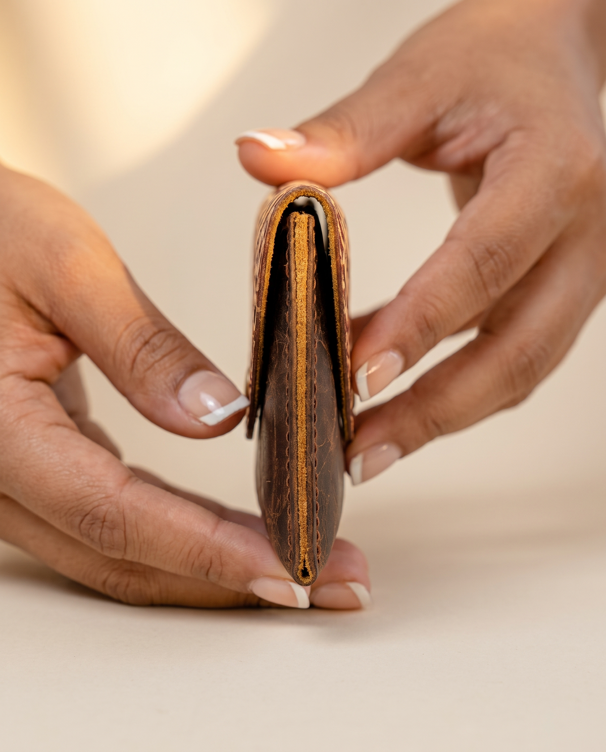 Crinkle brown leather wallet with tooled flap, held in hand, by Ya Qalbi