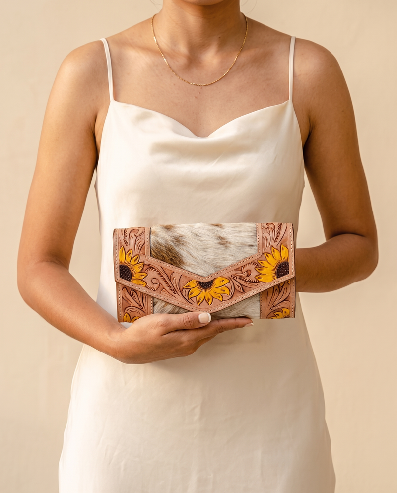 Cowhide envelope wallet with sunflower tooled frame, worn by a model, by Ya Qalbi