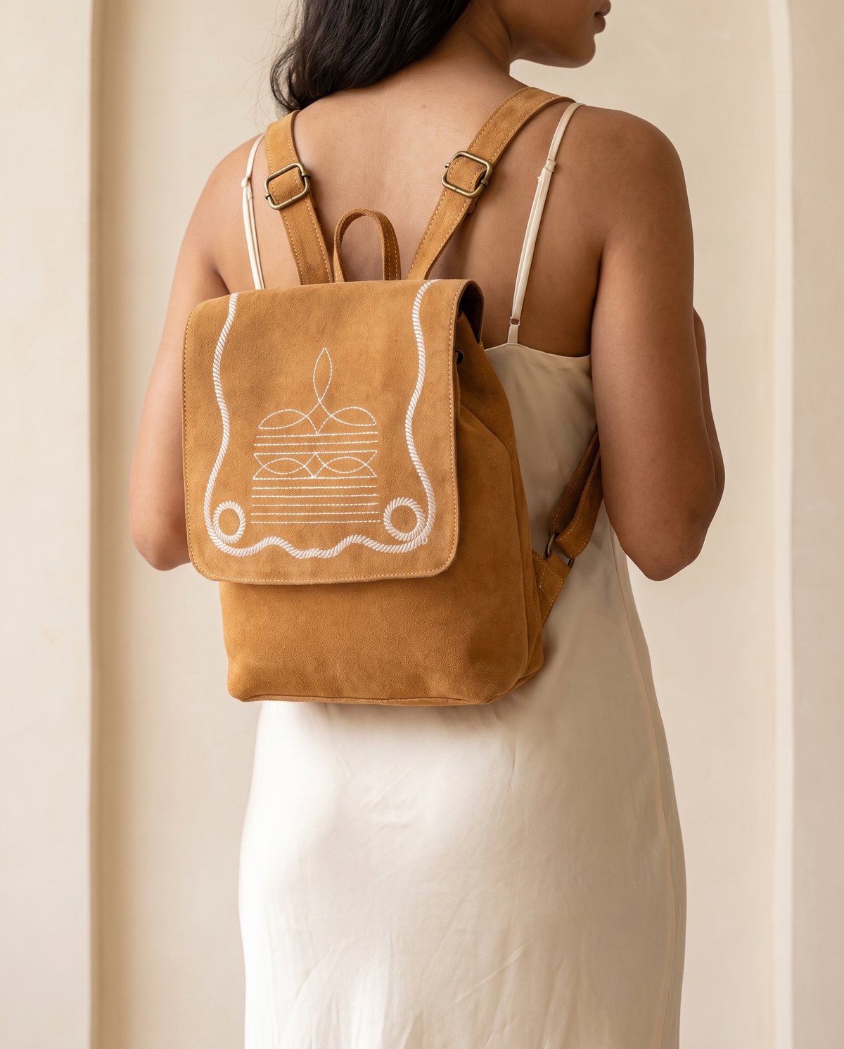 Woman wearing tan suede bootstitch backpack
