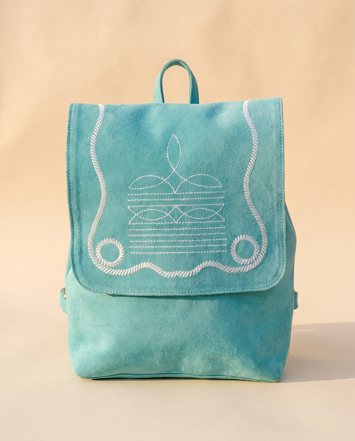 Turquoise suede drawstring backpack with bootstitch flap