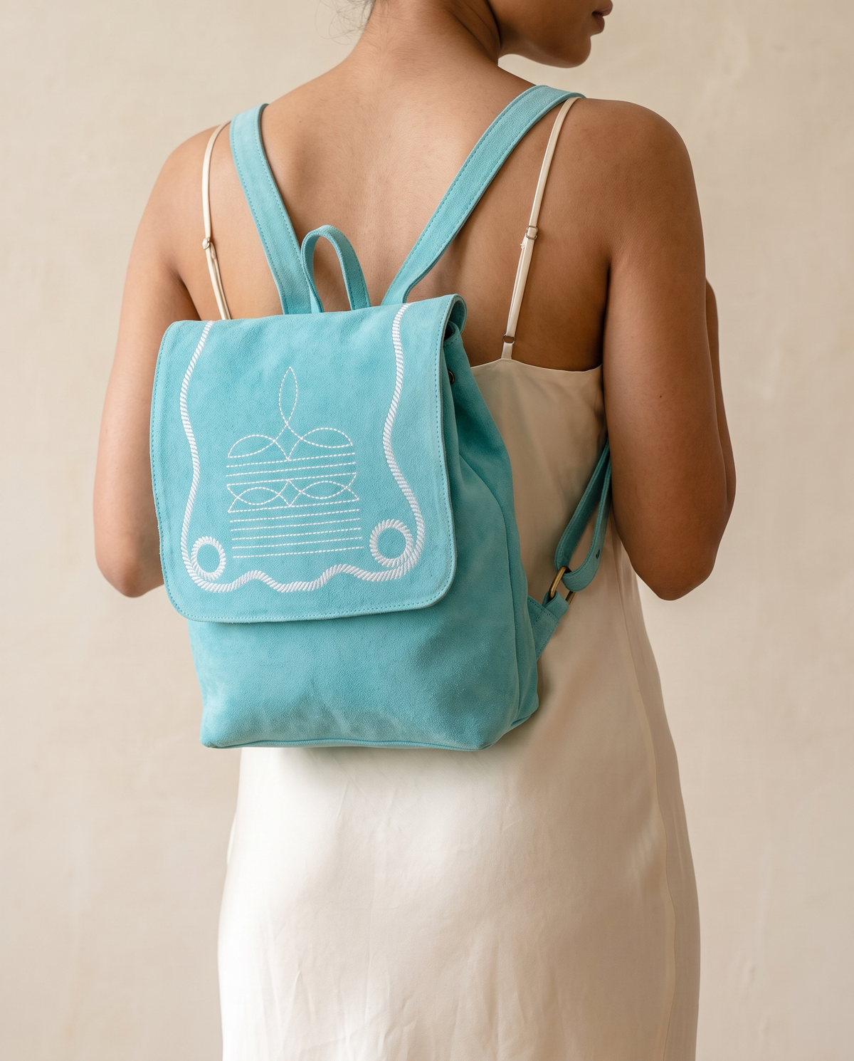 Woman wearing turquoise suede bootstitch backpack