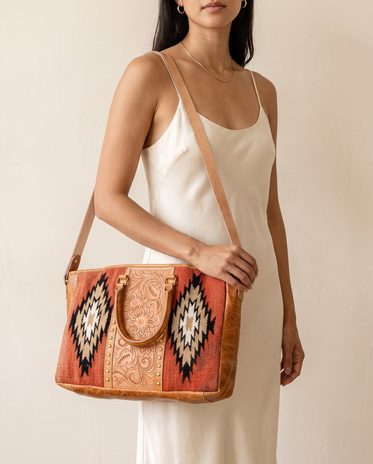 Rust Aztec woven leather zip tote with studded tooled strip, worn on the shoulder, by Ya Qalbi