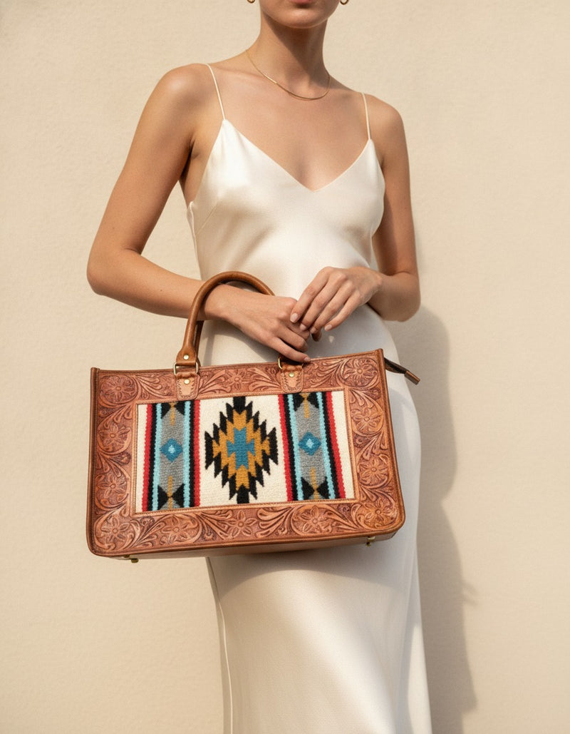 Cream serape panel tote with hand-tooled leather frame, worn by a model, by Ya Qalbi