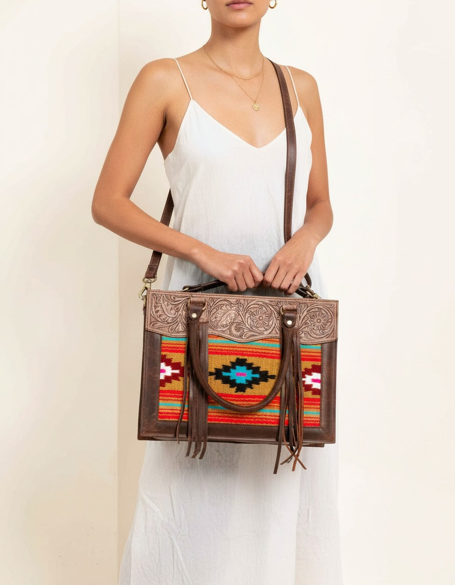 Orange serape fringe tote with tooled leather top, worn by a model, by Ya Qalbi