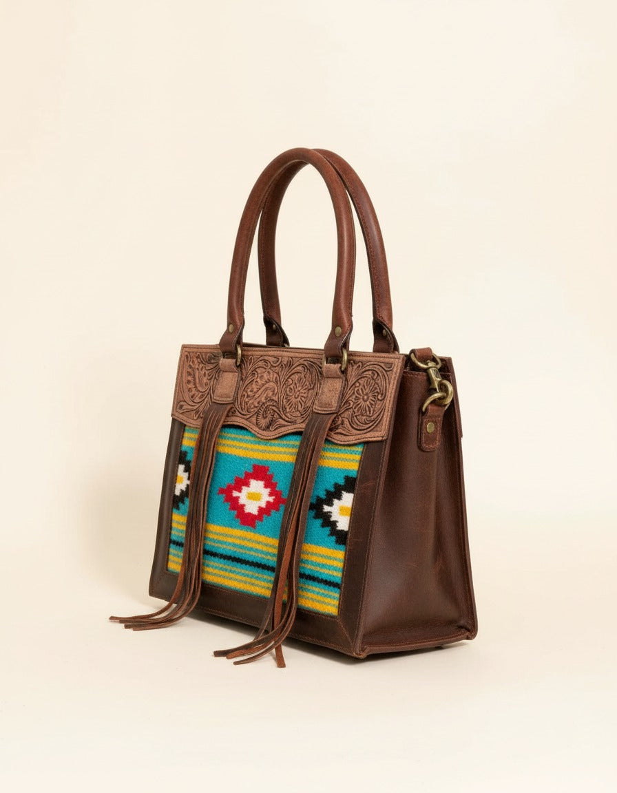 Turquoise and yellow serape fringe tote with tooled leather top, angled view, by Ya Qalbi