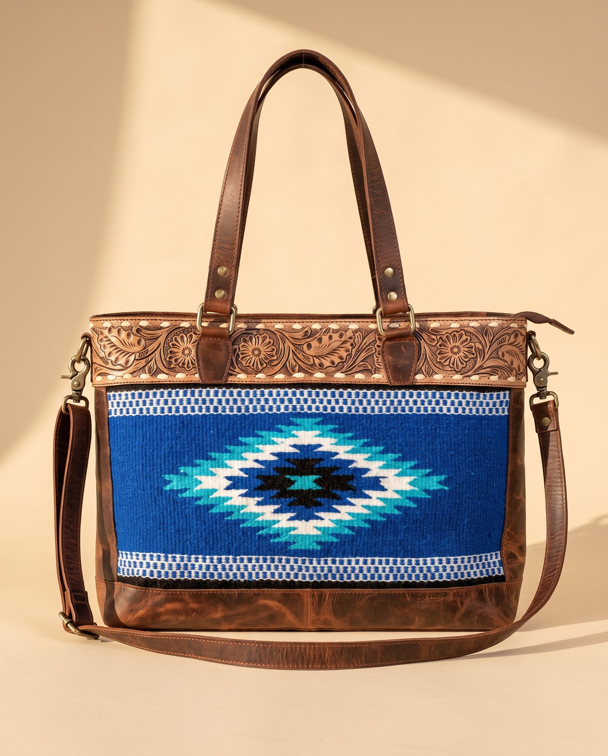 Blue serape woven zip tote with tooled leather band, front view, by Ya Qalbi