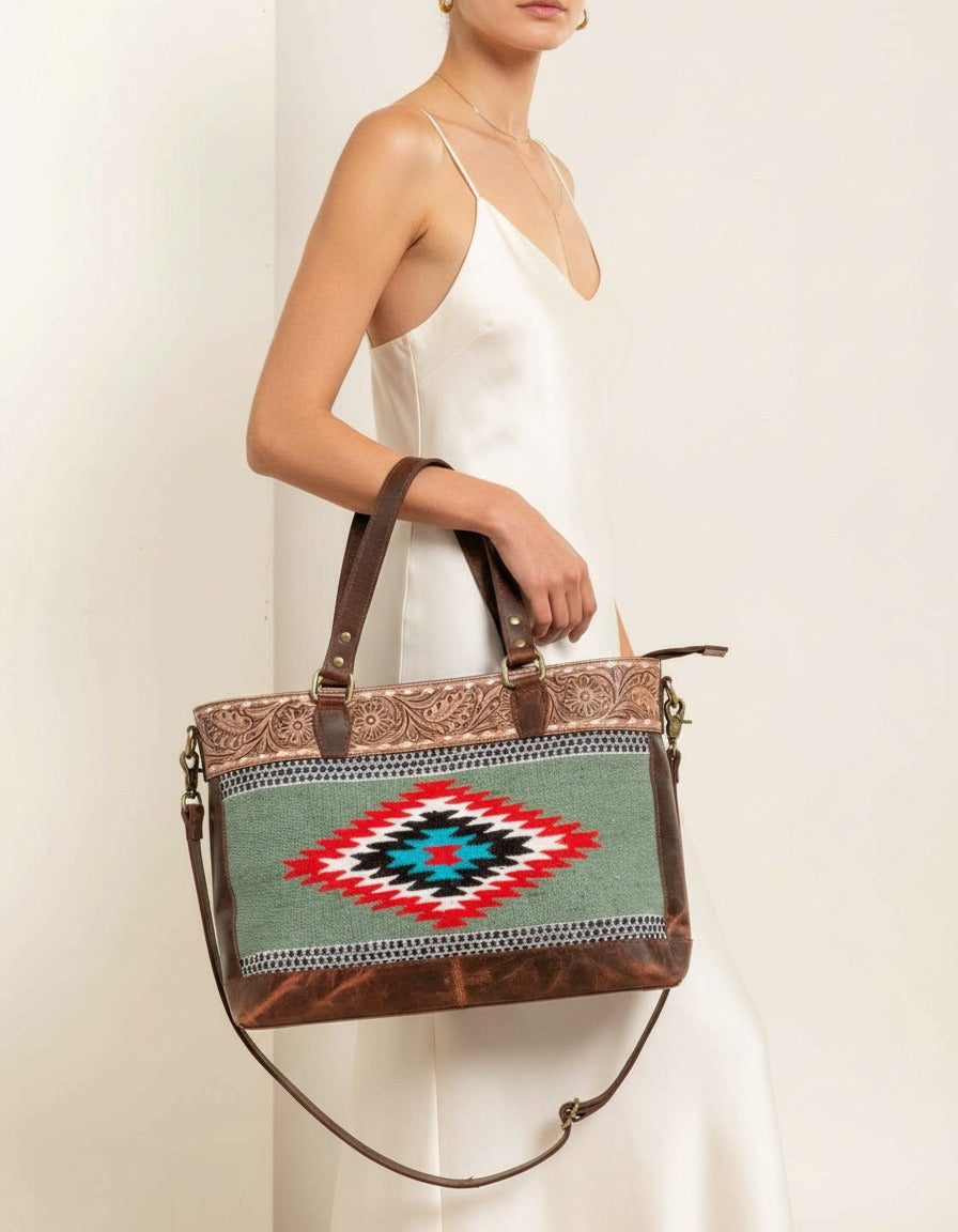 Sage serape woven zip tote with tooled leather band, worn by a model, by Ya Qalbi
