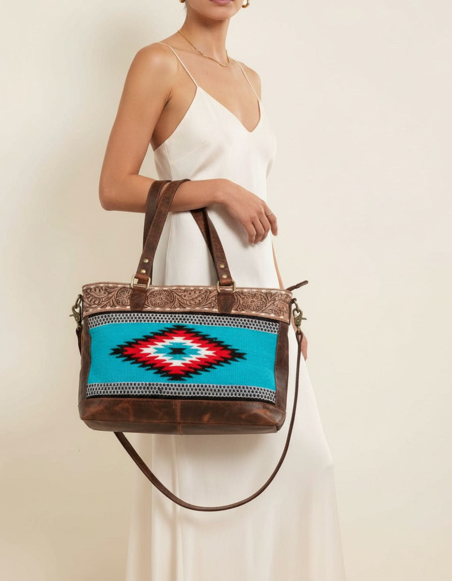 Turquoise serape woven zip tote with tooled leather band, worn by a model, by Ya Qalbi