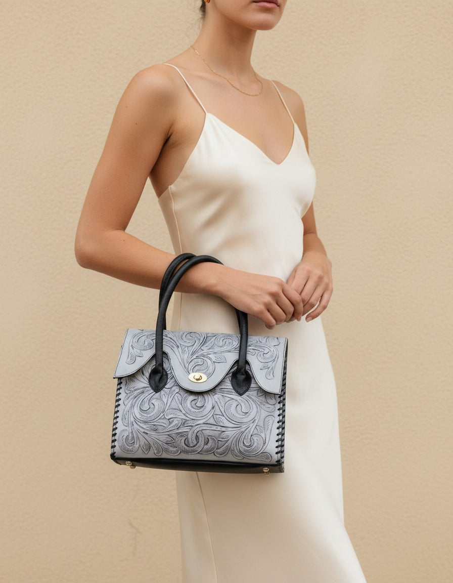 Grey hand-tooled leather top-handle handbag, worn by a model, by Ya Qalbi