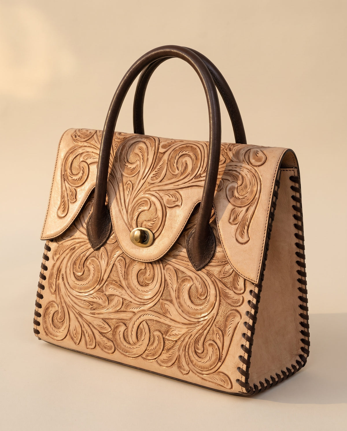 Tan hand-tooled leather top-handle handbag, angled view, by Ya Qalbi