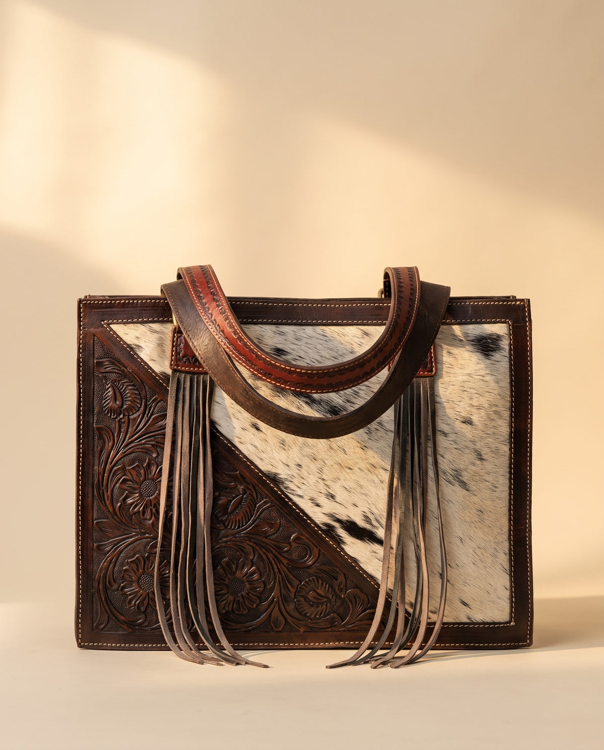 Dark brown tooled triangle hair-on cowhide leather tote with fringe, front view, by Ya Qalbi